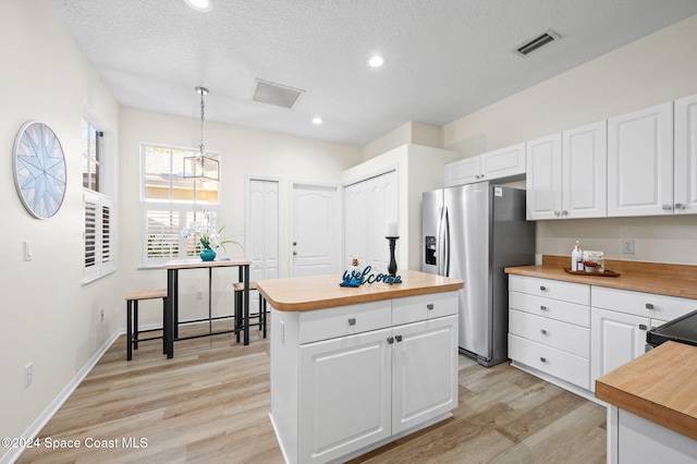 kitchen featuring pendant lighting, white cabinets, stainless steel fridge with ice dispenser, and light hardwood / wood-style flooring