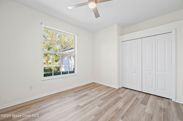 unfurnished bedroom featuring ceiling fan, light wood-type flooring, a textured ceiling, and a closet