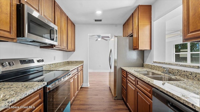 kitchen with sink, dark hardwood / wood-style floors, ceiling fan, light stone countertops, and stainless steel appliances