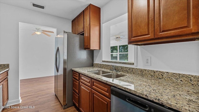 kitchen featuring light stone countertops, stainless steel dishwasher, ceiling fan, sink, and light hardwood / wood-style floors