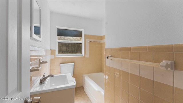 bathroom featuring a washtub, tile patterned floors, toilet, vanity, and tile walls