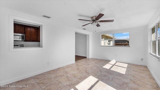 tiled spare room with ceiling fan and a textured ceiling