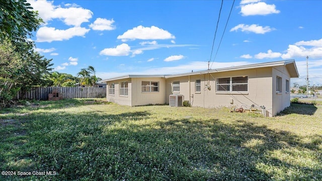 back of property featuring a yard and central AC