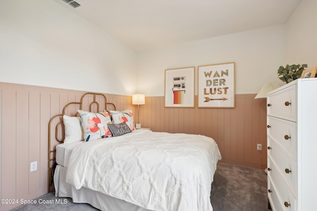 carpeted bedroom featuring wood walls