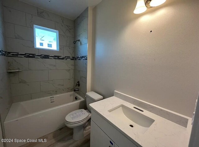 full bathroom featuring tiled shower / bath, vanity, and toilet