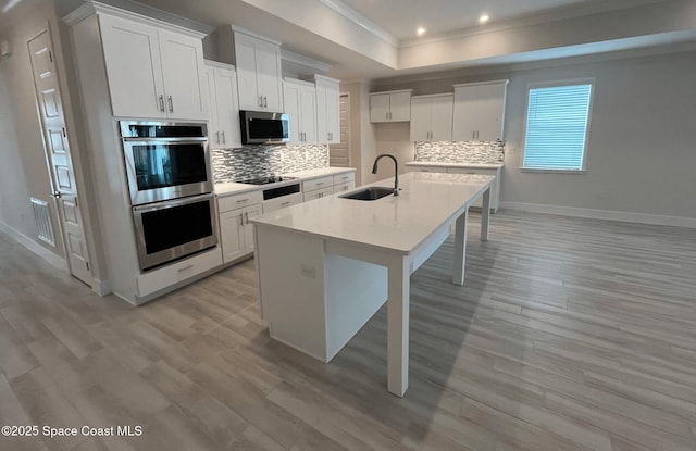 kitchen featuring sink, a breakfast bar area, appliances with stainless steel finishes, a kitchen island with sink, and white cabinetry