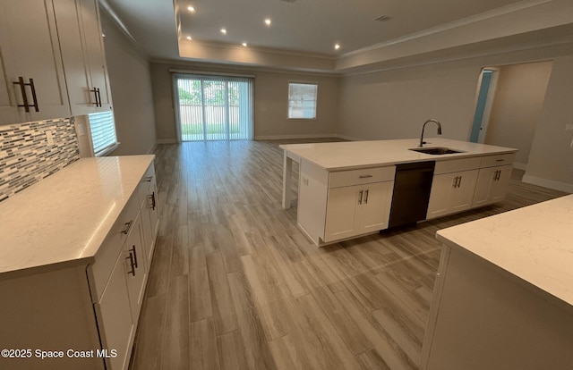 kitchen with sink, white cabinetry, a tray ceiling, black dishwasher, and a kitchen island with sink