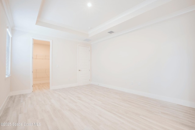 spare room with crown molding, light hardwood / wood-style floors, and a raised ceiling