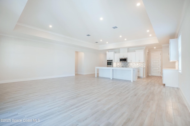 unfurnished living room with crown molding, light wood-type flooring, and a tray ceiling