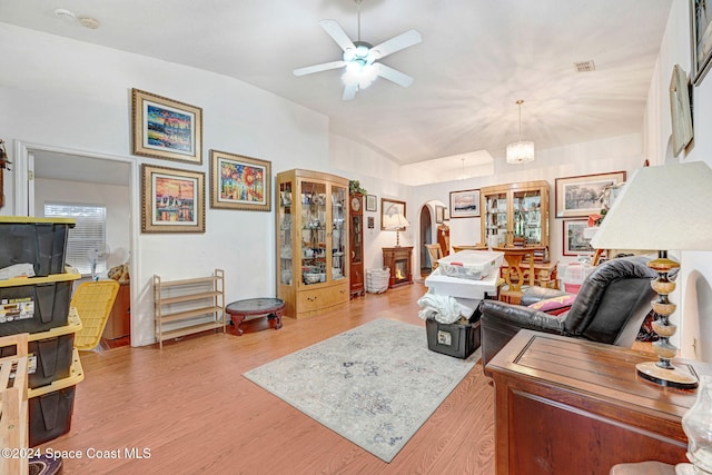 living room featuring light hardwood / wood-style flooring, ceiling fan with notable chandelier, and lofted ceiling