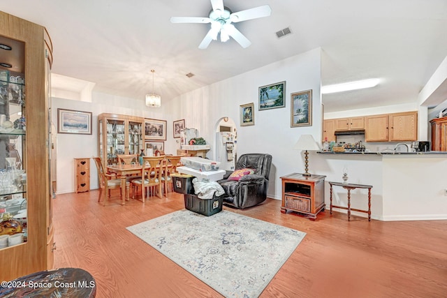 living room featuring ceiling fan with notable chandelier and light hardwood / wood-style flooring