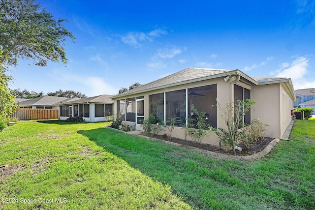 rear view of house featuring a lawn and a sunroom