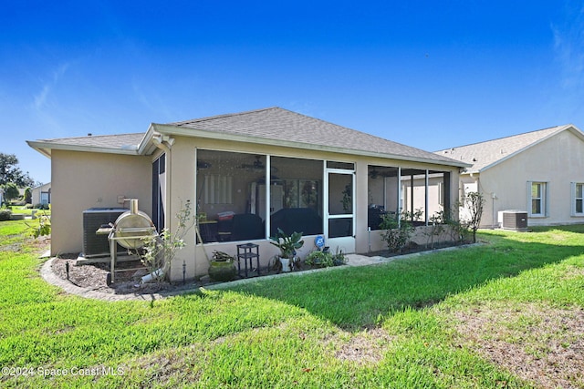 rear view of house featuring a sunroom, central AC unit, and a yard