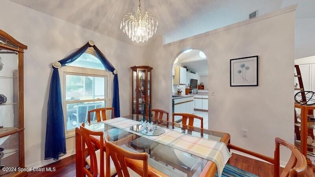 dining area with arched walkways, visible vents, baseboards, and wood finished floors