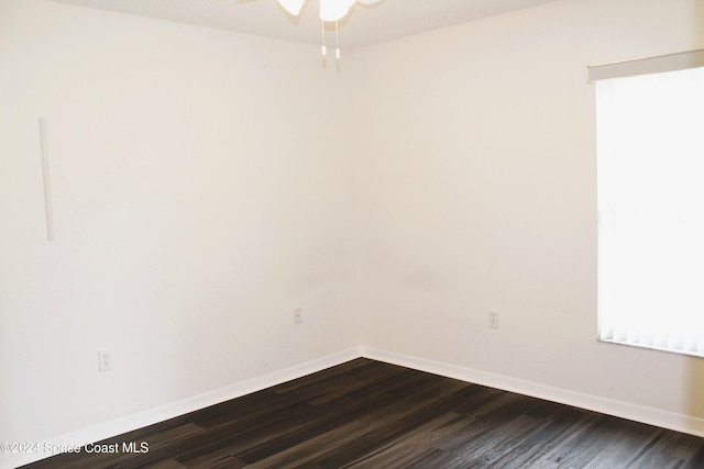 empty room featuring baseboards and dark wood-style flooring