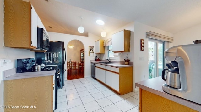 kitchen with arched walkways, dishwasher, light countertops, black microwave, and a sink