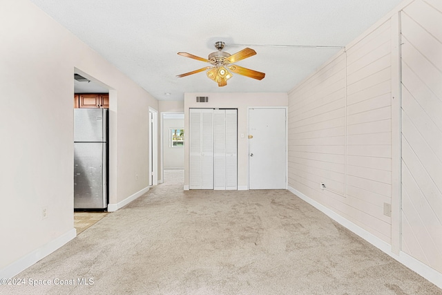 carpeted spare room with a textured ceiling and ceiling fan