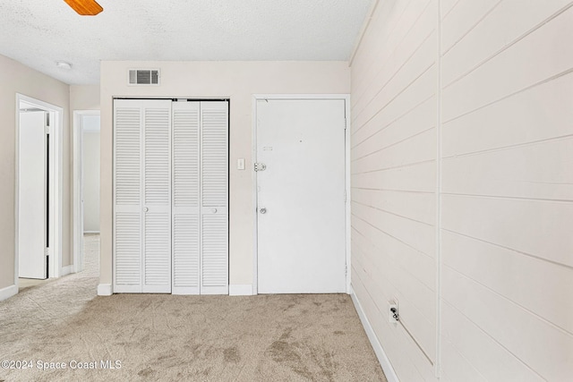 unfurnished bedroom with a textured ceiling, light colored carpet, and ceiling fan