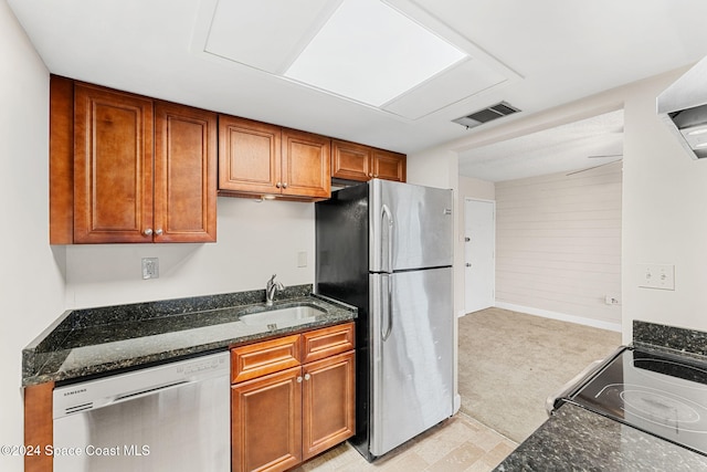 kitchen featuring sink, dark stone counters, and appliances with stainless steel finishes