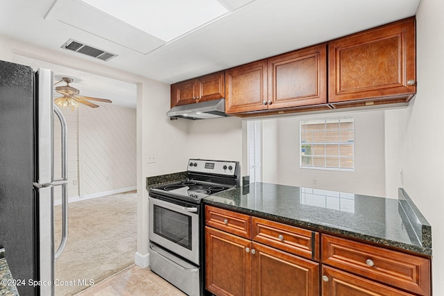 kitchen featuring light carpet, kitchen peninsula, stainless steel appliances, ceiling fan, and dark stone countertops