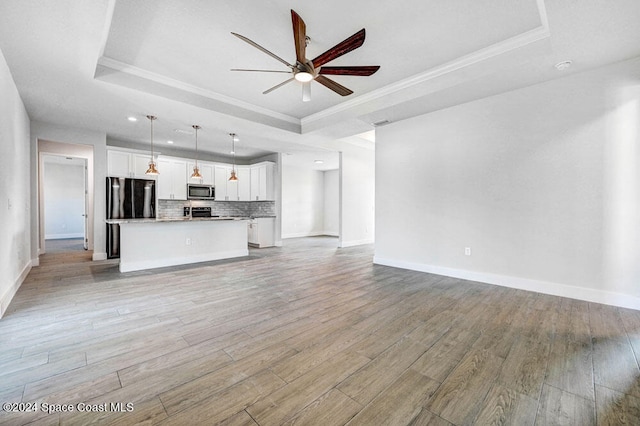 unfurnished living room featuring crown molding, a raised ceiling, and light hardwood / wood-style flooring