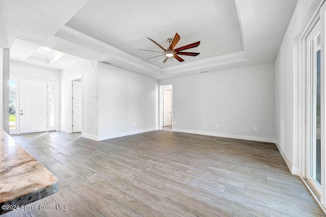 unfurnished living room with hardwood / wood-style flooring, ornamental molding, and a raised ceiling