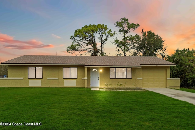 ranch-style house featuring a garage and a yard