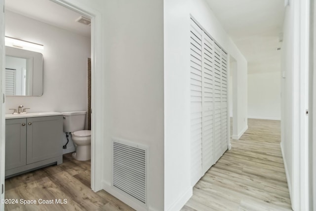 corridor with light hardwood / wood-style floors and sink