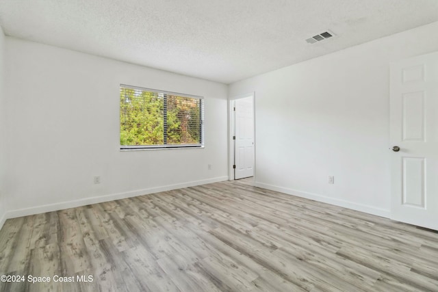 unfurnished room featuring light hardwood / wood-style floors and a textured ceiling