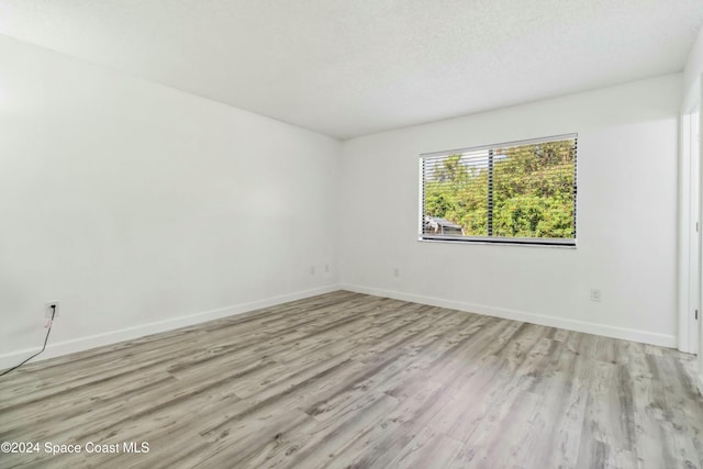 unfurnished room with light hardwood / wood-style flooring and a textured ceiling