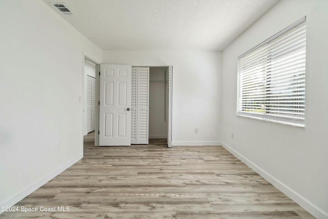 unfurnished bedroom featuring light hardwood / wood-style flooring and a textured ceiling