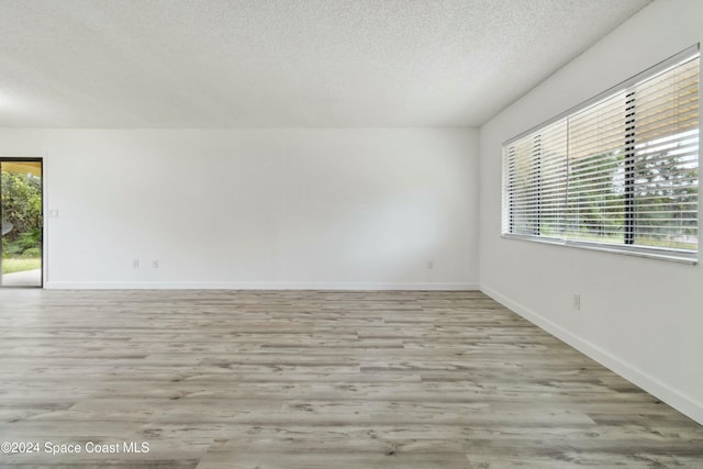 unfurnished room with light hardwood / wood-style floors and a textured ceiling