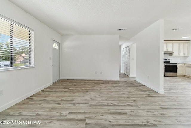 unfurnished living room featuring a textured ceiling and light hardwood / wood-style flooring