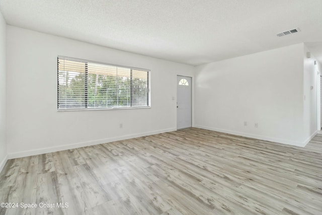 spare room with light hardwood / wood-style flooring and a textured ceiling