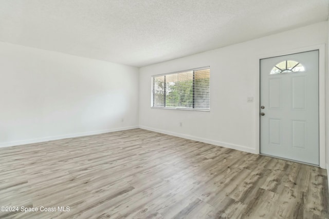 entrance foyer with light hardwood / wood-style floors and a textured ceiling