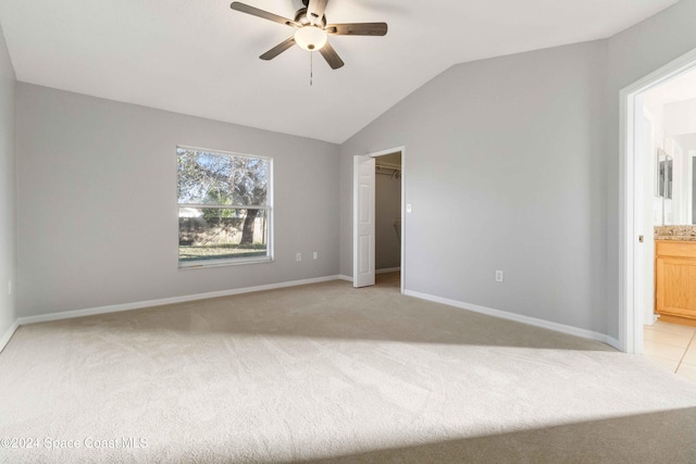 unfurnished bedroom featuring ceiling fan, vaulted ceiling, light carpet, and ensuite bath