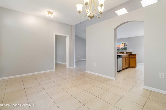 tiled empty room featuring an inviting chandelier