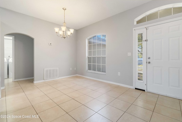 entryway with washing machine and clothes dryer, light tile patterned flooring, and a notable chandelier