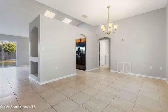 tiled empty room featuring a chandelier