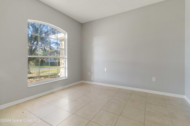 empty room featuring a textured ceiling and light tile patterned flooring