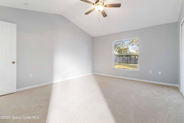 spare room featuring ceiling fan, lofted ceiling, and light carpet