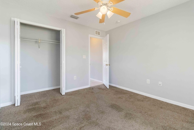 unfurnished bedroom with carpet, a textured ceiling, a closet, and ceiling fan