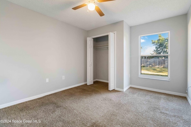 unfurnished bedroom with carpet flooring, ceiling fan, a closet, and a textured ceiling