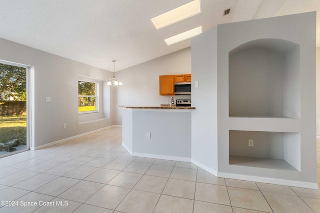 interior space featuring lofted ceiling with skylight, light tile patterned floors, and an inviting chandelier