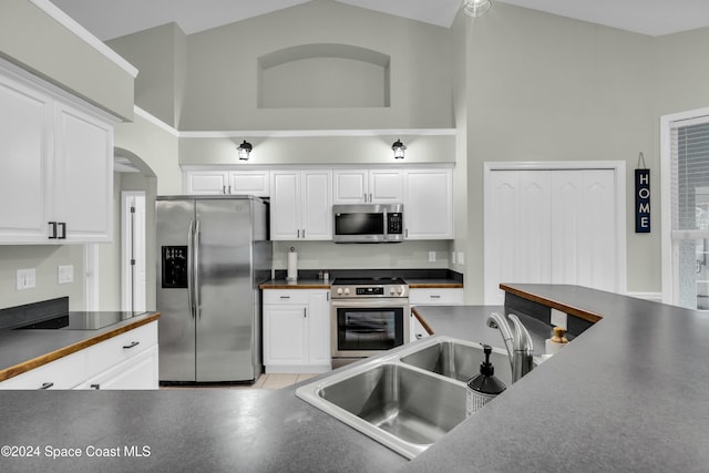 kitchen featuring white cabinets, stainless steel appliances, high vaulted ceiling, and sink