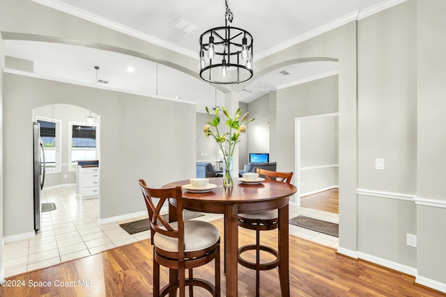 dining area with crown molding, light hardwood / wood-style flooring, and a notable chandelier