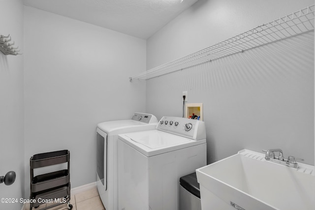 clothes washing area with a textured ceiling, light tile patterned floors, sink, and separate washer and dryer