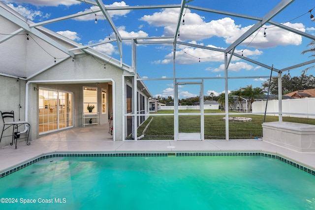 view of pool featuring a lawn, glass enclosure, and a patio area