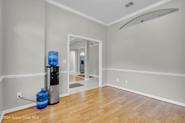 empty room featuring ornamental molding and light wood-type flooring