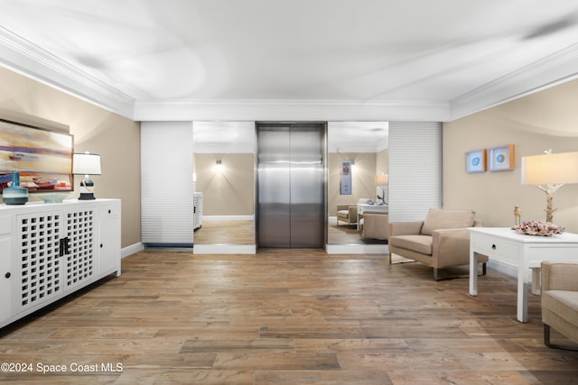 living area with elevator, light hardwood / wood-style floors, and ornamental molding